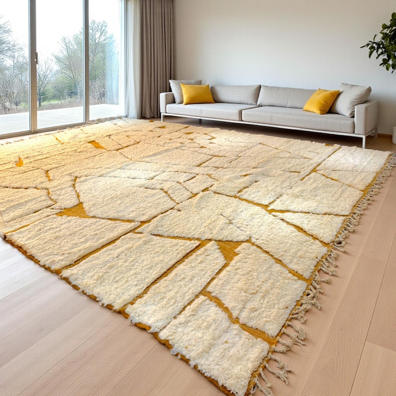 Handmade Moroccan rug in a soft ivory base with striking mustard yellow (Thai Curry) abstract lines. Woven by Berber artisans in pure wool, this rug blends tradition and modern style. Its geometric tribal pattern and warm tones make it perfect for living rooms, bedrooms, or creative interiors. Durable, eco-friendly, and soft underfoot, this ivory and mustard Berber carpet adds Moroccan charm and luxury to boho, modern, or eclectic home decor.