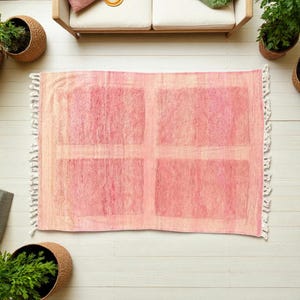 Handwoven Moroccan wool area rug in soft solid pink with a plush, high-pile texture and natural cream wool fringes. Made by Amazigh artisans in the Atlas Mountains, this minimalist Beni Ourain-style rug brings warmth, softness, and authentic Moroccan craftsmanship to modern boho or minimalist interiors.
