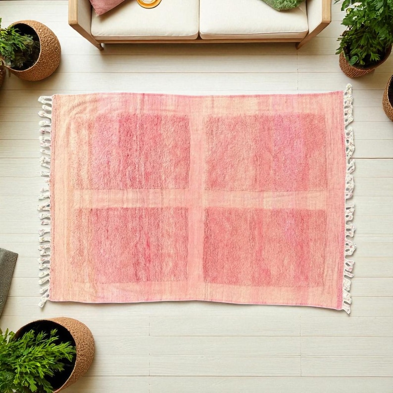 Handwoven Moroccan wool area rug in soft solid pink with a plush, high-pile texture and natural cream wool fringes. Made by Amazigh artisans in the Atlas Mountains, this minimalist Beni Ourain-style rug brings warmth, softness, and authentic Moroccan craftsmanship to modern boho or minimalist interiors.