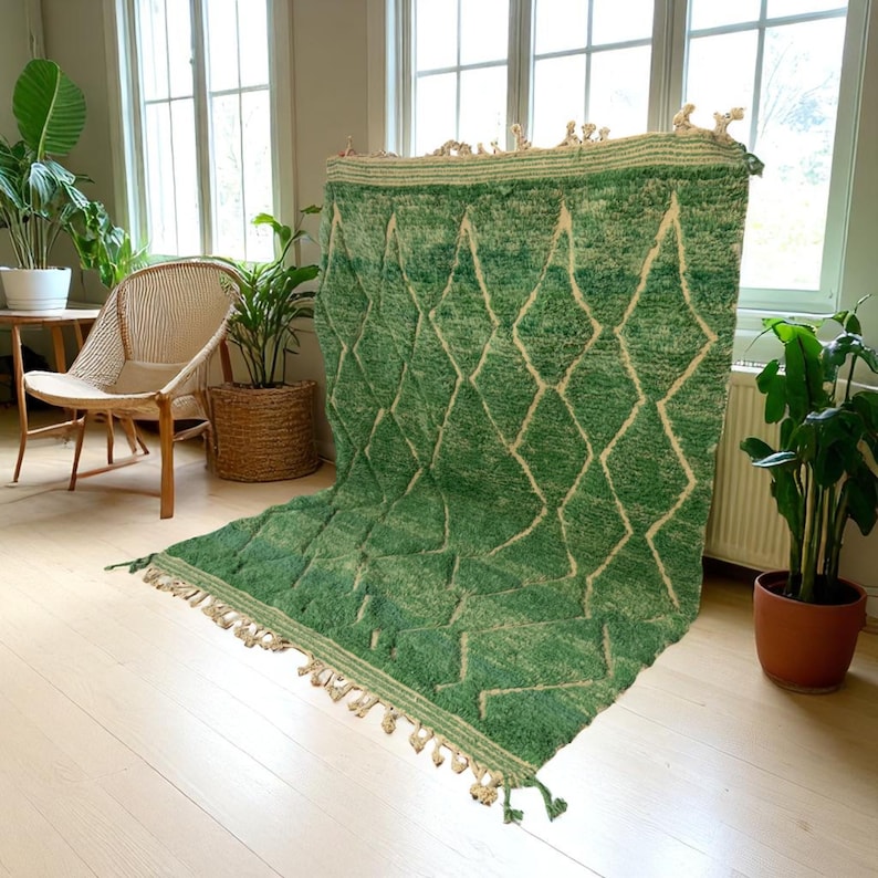 Green Moroccan wool rug with cream diamond lattice pattern, handmade in Beni Ourain style. Styled in a bright modern boho room with plants, rattan furniture, and natural light. The rug has a plush texture, tribal design, and fringe details, making it perfect for earthy, creative, or minimalist interiors. Crafted by Berber artisans, it's soft, thick, and ethically made using traditional weaving techniques.