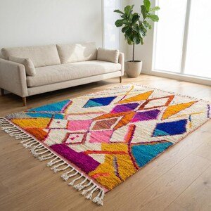 Authentic handmade Moroccan Boujaad rug featuring bold geometric diamond patterns in vibrant multicolor — electric blue, fuchsia pink, orange, yellow and purple on ivory wool background. Hand-knotted by Berber artisans in Morocco using natural wool. Perfect boho statement rug for living room, bedroom or dining room. One-of-a-kind colorful area rug with traditional fringe.