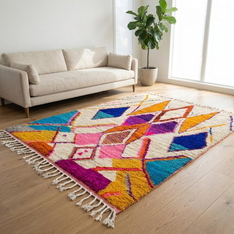 Authentic handmade Moroccan Boujaad rug featuring bold geometric diamond patterns in vibrant multicolor — electric blue, fuchsia pink, orange, yellow and purple on ivory wool background. Hand-knotted by Berber artisans in Morocco using natural wool. Perfect boho statement rug for living room, bedroom or dining room. One-of-a-kind colorful area rug with traditional fringe.
