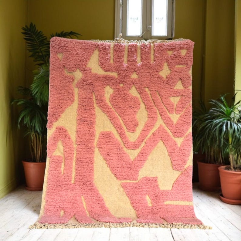 Modern abstract Moroccan Beni Mrirt rug featuring soft pink and beige tones with artistic organic patterns. Handwoven with premium wool by Amazigh artisans in Morocco. This boho-chic rug is perfect for adding an artistic touch to contemporary, minimalist, or eclectic interiors. Plush and cozy underfoot, it’s ideal for living rooms, bedrooms, and stylish creative spaces. Unique handmade piece crafted with passion and heritage.