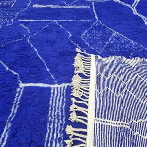 Striking handmade Moroccan rug in bold cobalt blue with white tribal Amazigh symbols. Crafted from natural wool, this unique Berber rug features traditional abstract lines and diamond motifs, perfect for adding a splash of color and culture to modern interiors. Ideal for boho, eclectic, or contemporary homes looking for a statement piece. Soft texture and timeless authenticity.