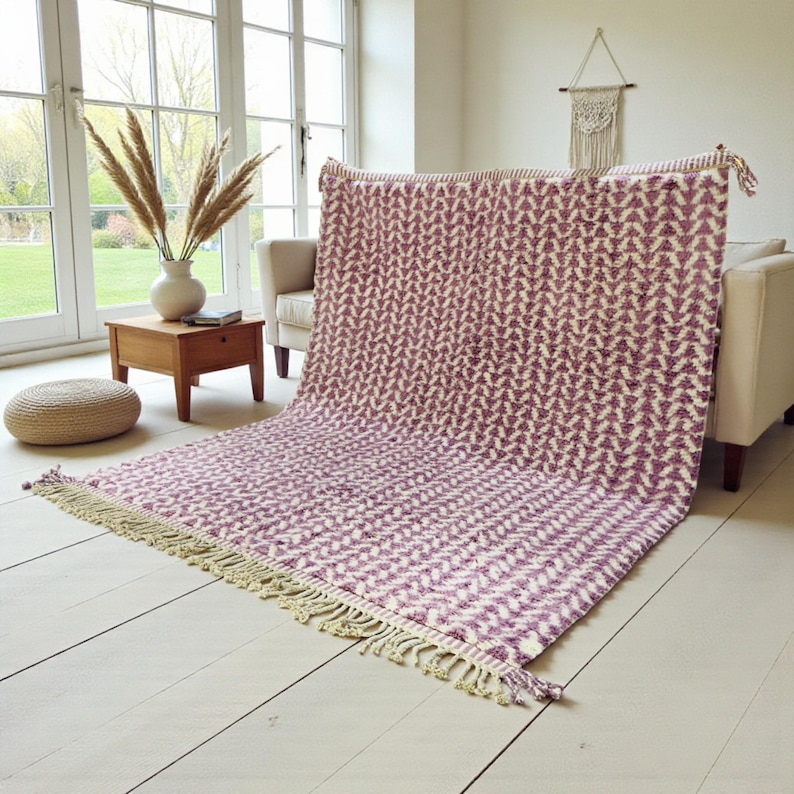 Handwoven Moroccan wool rug in wistful mauve and cream tones. Features a soft geometric pattern with textured pile and hand-knotted fringes. Perfect for living rooms, bedrooms, or boho interiors. Made from 100% natural wool by Berber artisans in Morocco. This handmade rug adds warmth, elegance, and Moroccan authenticity to modern or vintage-style spaces.