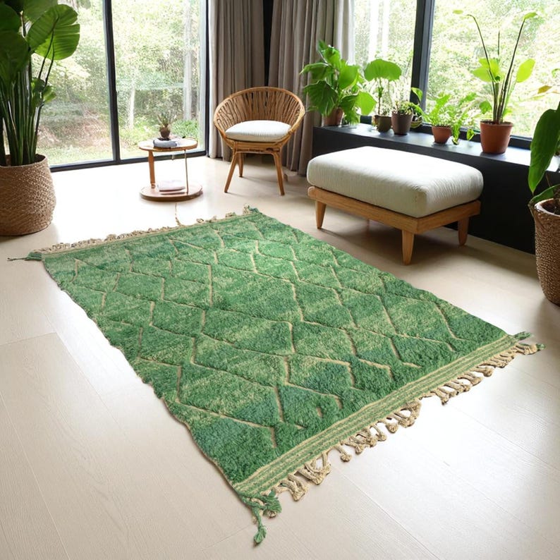 Green Moroccan wool rug with cream diamond lattice pattern, handmade in Beni Ourain style. Styled in a bright modern boho room with plants, rattan furniture, and natural light. The rug has a plush texture, tribal design, and fringe details, making it perfect for earthy, creative, or minimalist interiors. Crafted by Berber artisans, it's soft, thick, and ethically made using traditional weaving techniques.