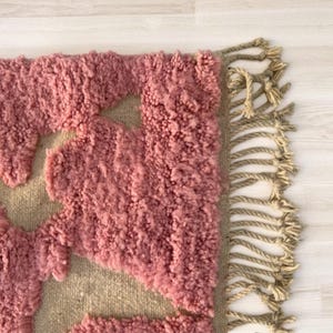 Modern abstract Moroccan Beni Mrirt rug featuring soft pink and beige tones with artistic organic patterns. Handwoven with premium wool by Amazigh artisans in Morocco. This boho-chic rug is perfect for adding an artistic touch to contemporary, minimalist, or eclectic interiors. Plush and cozy underfoot, it’s ideal for living rooms, bedrooms, and stylish creative spaces. Unique handmade piece crafted with passion and heritage.