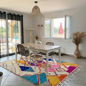 Authentic handmade Moroccan Boujaad rug featuring bold geometric diamond patterns in vibrant multicolor — electric blue, fuchsia pink, orange, yellow and purple on ivory wool background. Hand-knotted by Berber artisans in Morocco using natural wool. Perfect boho statement rug for living room, bedroom or dining room. One-of-a-kind colorful area rug with traditional fringe.