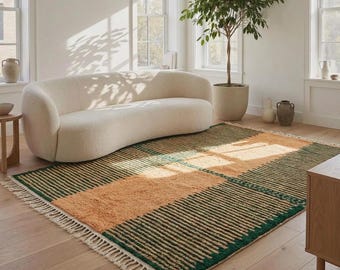 Può includere: Un tappeto rettangolare caratterizzato da un motivo a blocchi color beige alternati a sezioni a righe verde scuro. Il tappeto presenta un pelo testurizzato ed è rifinito con frange color crema lungo i bordi corti, su un pavimento in legno.