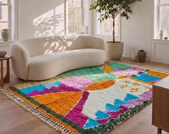 Può includere: Un tappeto rettangolare caratterizzato da un vivace motivo geometrico nei toni dell'arancione, magenta, verde acqua e bianco. Il tappeto presenta un pelo spesso e strutturato, rifinito con frange color crema sui lati corti per un tocco distintivo.