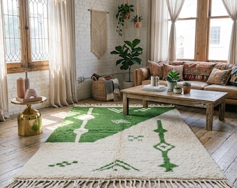 May include: A rectangular area rug featuring a split design of cream and green wool with a high-pile texture. The rug displays geometric patterns in green on the cream section and cream on the green section, finished with long fringe on both ends.