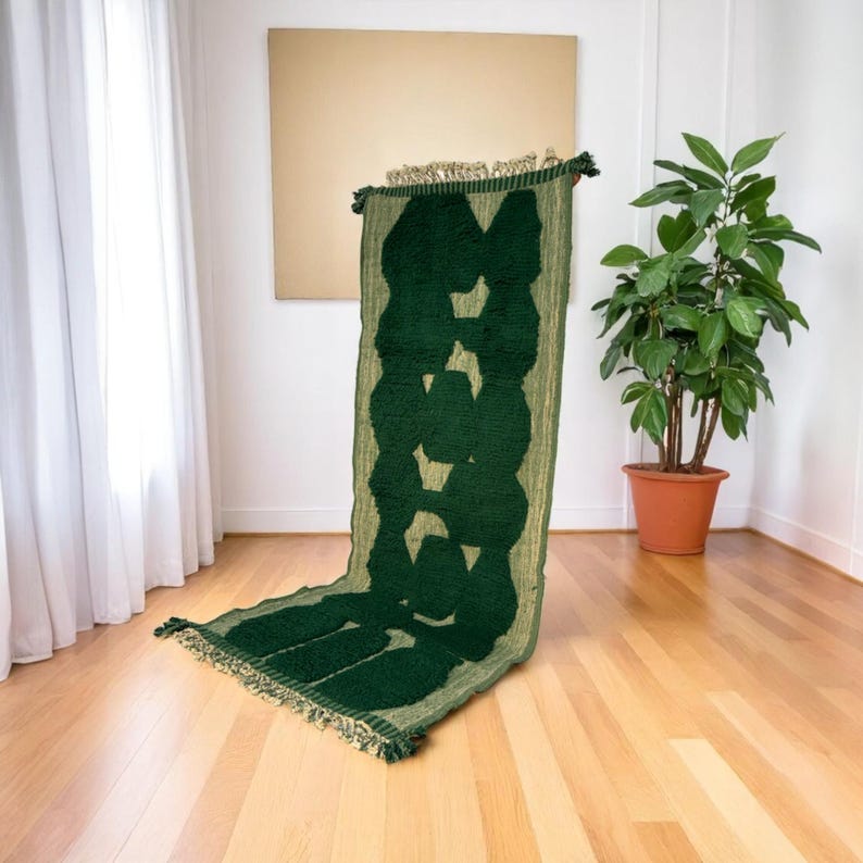 Extra-long Moroccan runner rug in deep green with bold organic patterns and beige wool base. This handcrafted Beni Ourain wool carpet is perfect for hallways, corridors, and modern interiors needing a unique, earthy touch. Made by Berber artisans using natural wool, it combines luxury softness and geometric structure. Ideal for minimalist, boho, or Japandi-style homes.