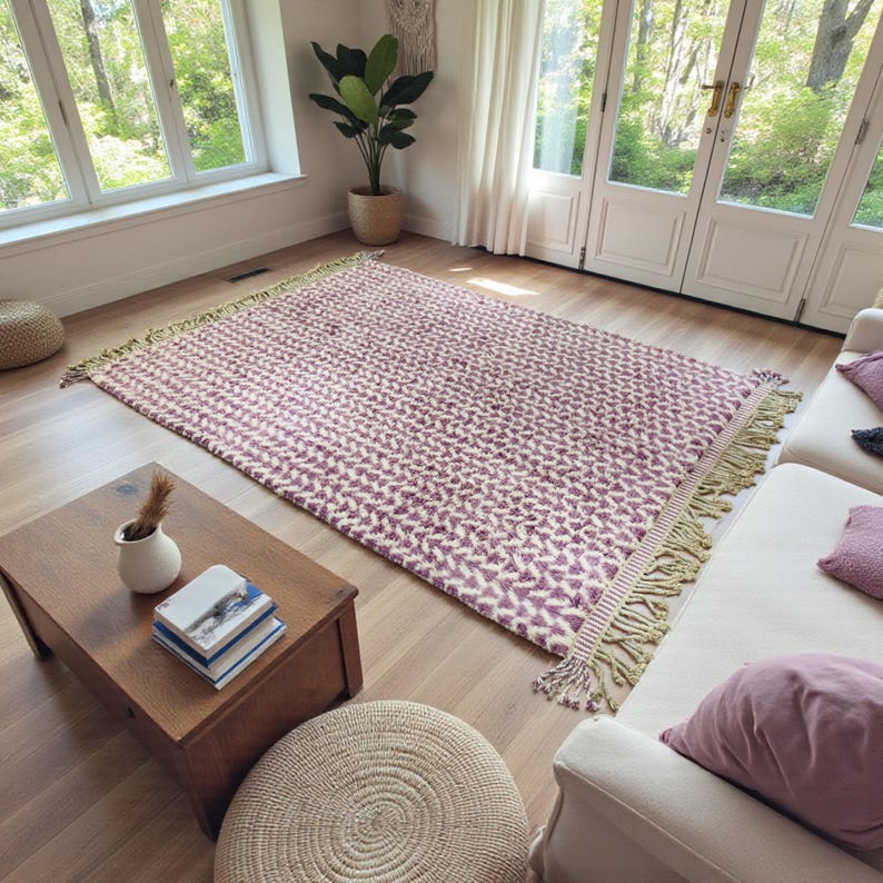 Handwoven Moroccan wool rug in wistful mauve and cream tones. Features a soft geometric pattern with textured pile and hand-knotted fringes. Perfect for living rooms, bedrooms, or boho interiors. Made from 100% natural wool by Berber artisans in Morocco. This handmade rug adds warmth, elegance, and Moroccan authenticity to modern or vintage-style spaces.