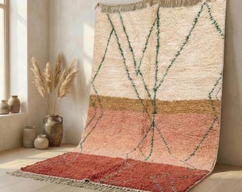 Può includere: Un tappeto rettangolare caratterizzato da un design a blocchi di colore crema, beige, pesca e terracotta. Il tappeto presenta una texture a pelo lungo con sottili linee geometriche verde scuro sulla superficie e frange sui bordi superiore e inferiore.
