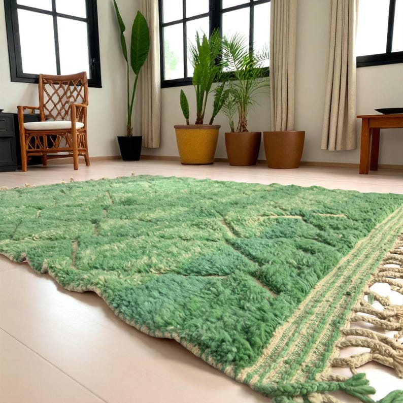 Green Moroccan wool rug with cream diamond lattice pattern, handmade in Beni Ourain style. Styled in a bright modern boho room with plants, rattan furniture, and natural light. The rug has a plush texture, tribal design, and fringe details, making it perfect for earthy, creative, or minimalist interiors. Crafted by Berber artisans, it's soft, thick, and ethically made using traditional weaving techniques.