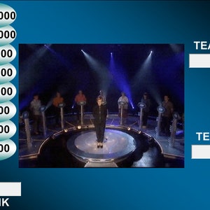 May include: A game show set with a large circular stage and a contestant standing in the centre. The stage has a series of podiums with lights. A scoreboard on the left side of the image displays amounts of money from £1,000 to £125,000. The text "TEAM 1" and "TEAM 2" are displayed on the right side of the image.