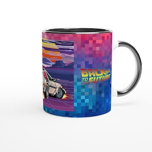 Puede incluir: Una taza de cerámica blanca con un borde y un asa negros. La taza presenta un diseño pixelado de un DeLorean, la máquina del tiempo de la película Regreso al futuro, conduciendo por una carretera con una puesta de sol en el fondo. El texto "Regreso al futuro" está impreso en la taza.