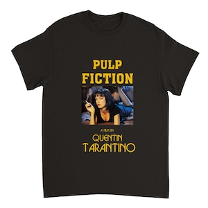May include: Black t-shirt with a yellow graphic of Mia Wallace from the movie Pulp Fiction. The graphic includes the text "Pulp Fiction" and "A film by Quentin Tarantino".