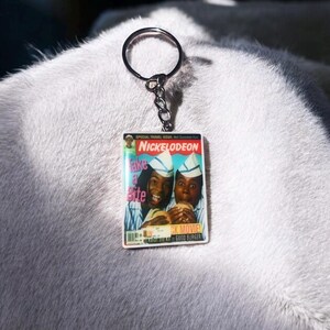May include: Keychain featuring a miniature magazine cover with the Nickelodeon logo and the text "Take a Bite." The image shows two people holding burgers. The keychain has a silver ring and chain.