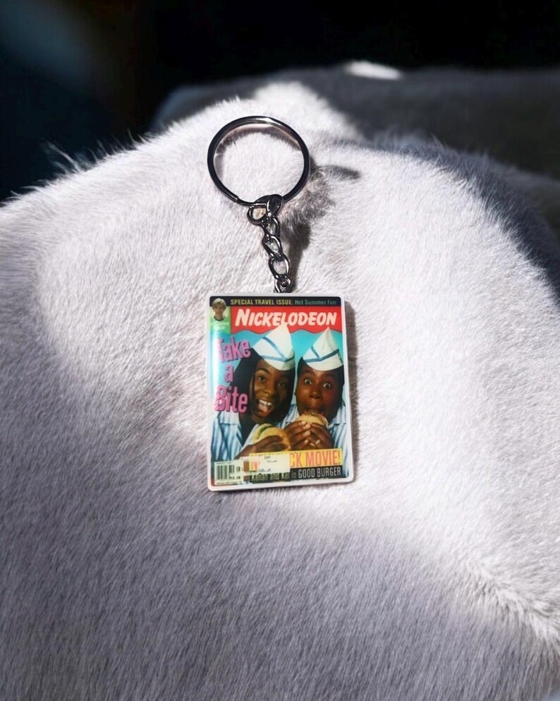 May include: Keychain featuring a miniature magazine cover with the Nickelodeon logo and the text "Take a Bite." The image shows two people holding burgers. The keychain has a silver ring and chain.