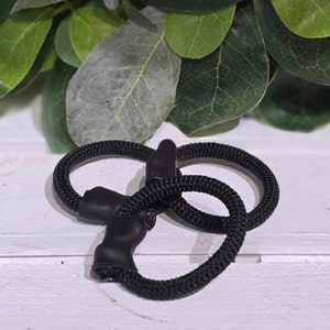 May include: Black elastic hair ties with a textured surface. The hair ties are knotted together.