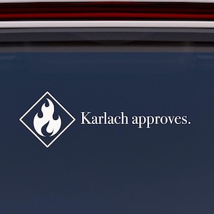 May include: White car window sticker featuring a diamond-shaped graphic with a flame design and the text "Karlach approves." in a clean font. The sticker is affixed to the rear window of a white car.