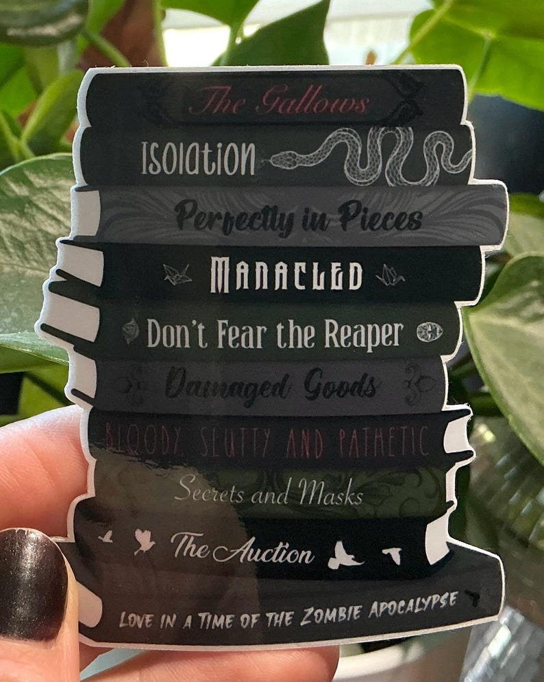K&ouml;nnte beinhalten: Ein Aufkleber mit einem Stapel von B&uuml;chern mit Titeln wie "The Gallows" und "Isolation". Die B&uuml;cher sind &uuml;berwiegend dunkel gef&auml;rbt mit wei&szlig;em Text und Illustrationen, darunter eine Schlange. Das untere Buch tr&auml;gt die Aufschrift "Love in a Time of the Zombie Apocalypse."