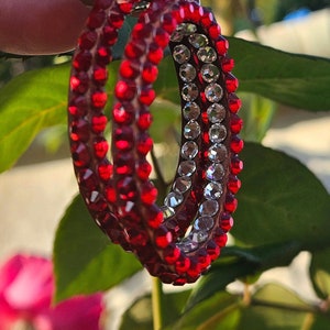 May include: A pair of hoop earrings with a double row of red and clear rhinestones.