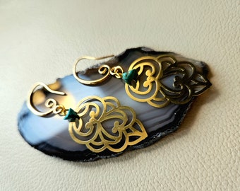May include: A pair of gold earrings with intricate filigree designs and turquoise accents. The earrings are displayed on a gray and white agate stone.