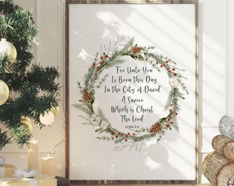 May include: A framed print with a Christmas wreath design and the text "For Unto You Is Born this Day In the City of David A Savior Which is Christ The Lord Luke 2:11." The print is displayed near a decorated Christmas tree and wrapped gifts.