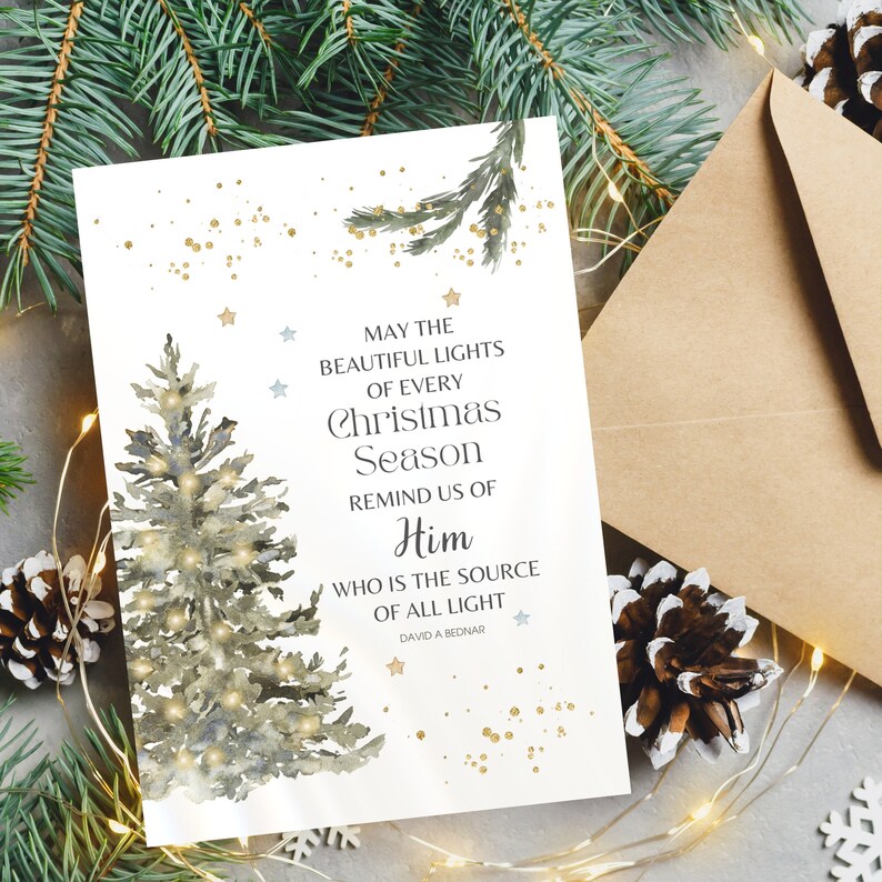 May include: A Christmas card featuring a watercolour illustration of a Christmas tree and the text "MAY THE BEAUTIFUL LIGHTS OF EVERY CHRISTMAS SEASON REMIND US OF HIM WHO IS THE SOURCE OF ALL LIGHT". Includes a brown envelope.