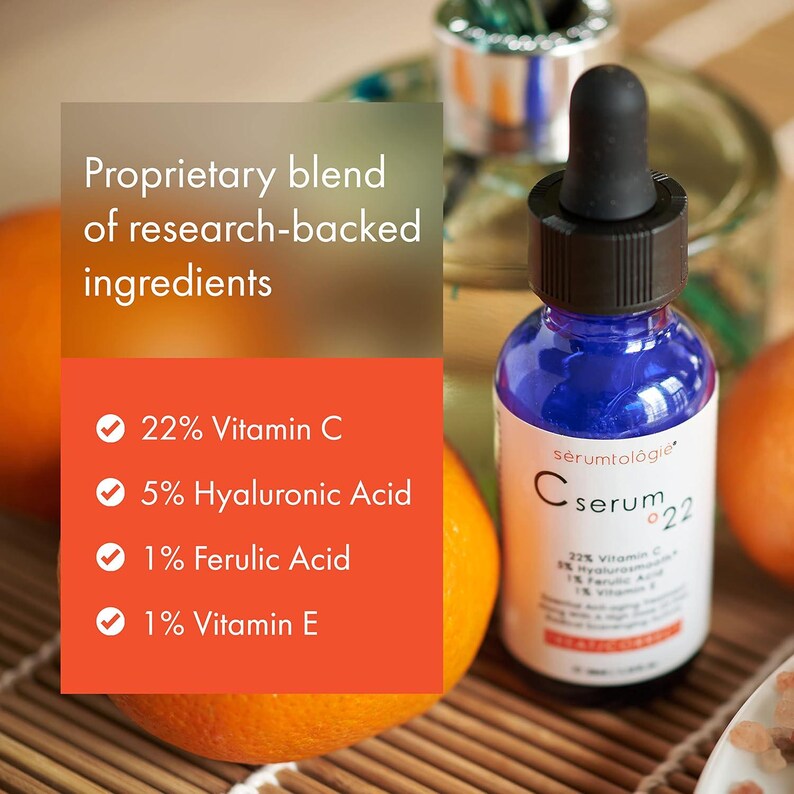 May include: A blue serum bottle with a black dropper sits next to an orange. The label reads "C serum 22" and lists ingredients: 22% Vitamin C, 5% Hyaluronic Acid, 1% Ferulic Acid, and 1% Vitamin E. The text "Proprietary blend of research-backed ingredients" is also visible.