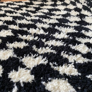 May include: Black and white chevron patterned rug with a fluffy texture.