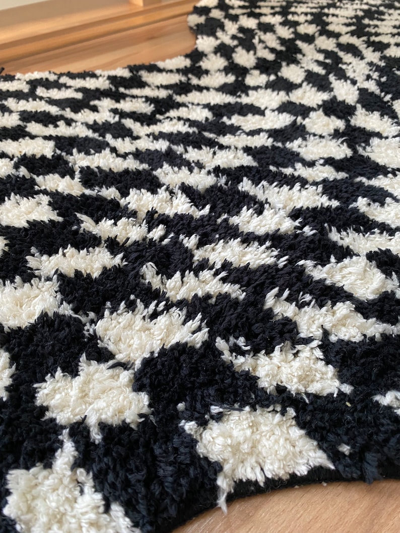 May include: Black and white chevron patterned rug with a fluffy texture.