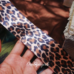 May include: A brown and black leopard print satin ribbon.