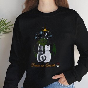 May include: Black sweatshirt featuring a graphic of two cats sitting on a globe with the text "Peace on Earth".