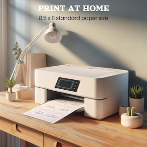 Peut inclure: Une imprimante blanche avec un bac &agrave; papier et une feuille de papier avec du texte imprim&eacute; dessus. L'imprimante est sur une table en bois avec une lampe et des plantes en arri&egrave;re-plan. Le texte sur le papier dit "IMPRIMER &Agrave; LA MAISON 8,5 x 11 format papier standard".