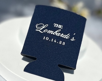 May include: A navy blue can cooler with white text that reads "THE Lombardi's 10.14.23".
