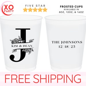May include: Two white frosted plastic cups with black text. The cup on the left has a floral design and the letter "J" with the text "Kim & Dean". The cup on the right has the text "The Johnsons 12 18 25".