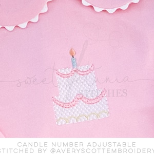 May include: A pink embroidered design of a mini birthday cake with a single candle on top. The cake has white frosting and pink accents. The text "CANDLE NUMBER ADJUSTABLE STITCHED BY @AVERYSSCOTTEMBROIDERY" is below the cake.