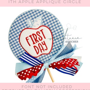 May include: A blue and white gingham circle with a red apple applique that says "FIRST DAY" in white letters. The circle is attached to a stick with blue, white, and red ribbon.