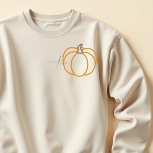 May include: A cream-coloured sweatshirt with an orange pumpkin outline design and a brown stem. The words "sweet stitches" are written in cursive. A cosy autumn-themed apparel item.