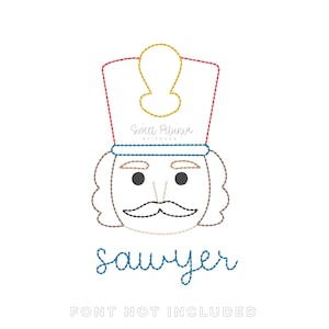 May include: Embroidered design of a nutcracker soldier's face with a red, gold, and blue hat. The name "sawyer" is written in blue script below the face. The text "FONT NOT INCLUDED" is at the bottom.