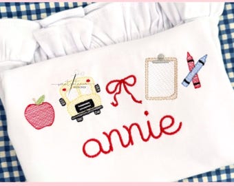 May include: White shirt with embroidered school-themed designs, including an apple, school bus, bow, clipboard, and crayons. The name "annie" is embroidered in red script. The text "BACK TO SCHOOL BOW LINE" is at the top.