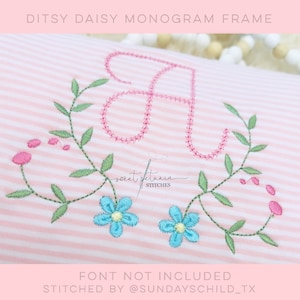 May include: A pink and white striped fabric with a pink embroidered letter "A" surrounded by green leaves and blue flowers. The text "Ditsy Daisy Monogram Frame" is at the top of the image. The text "sweet petunia stitches" is in the center of the image. The text "FONT NOT INCLUDED" is at the bottom of the image. The text "STITCHED BY @SUNDAYSCHILD_TX" is at the bottom of the image.