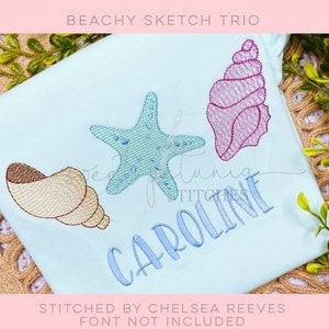 May include: A light blue t-shirt with a pink seashell, a blue starfish, and a brown seashell embroidered on it. The name "CAROLINE" is embroidered in blue cursive lettering below the seashells. The text "STITCHED BY CHELSEA REEVES FONT NOT INCLUDED" is printed below the design.