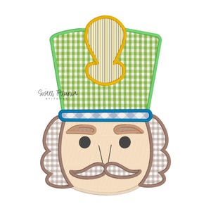 Puede incluir: Un diseño caprichoso de cara de cascanueces con un sombrero a cuadros verde y blanco y un acento dorado. La cara presenta una tez bronceada, ojos negros y un bigote marrón. El texto "Sweet Petunia Stitches" está en la imagen.