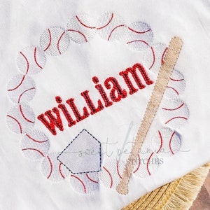May include: White embroidered baseball themed baby onesie with the name "William" in red lettering.