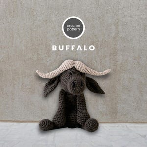 May include: Crochet pattern for a brown buffalo amigurumi with beige horns. The buffalo is sitting with its legs crossed and has a friendly expression.