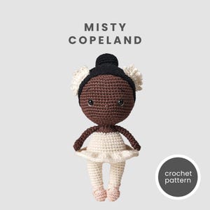 Puede incluir: Patrón de crochet para una muñeca bailarina con piel marrón, cabello negro y un tutú blanco. La muñeca lleva zapatillas de ballet rosas. El patrón es de Misty Copeland.
